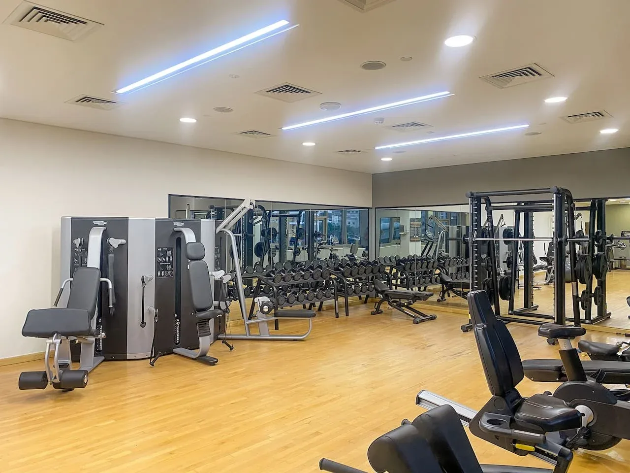 A gym with weight machines, dumbbells, and mirrored walls.