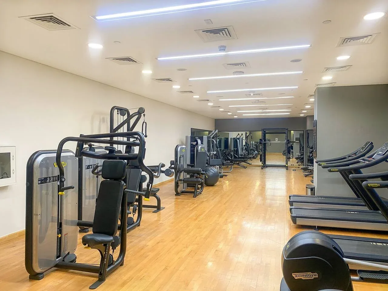 A spacious gym with exercise machines and treadmills along the sides.