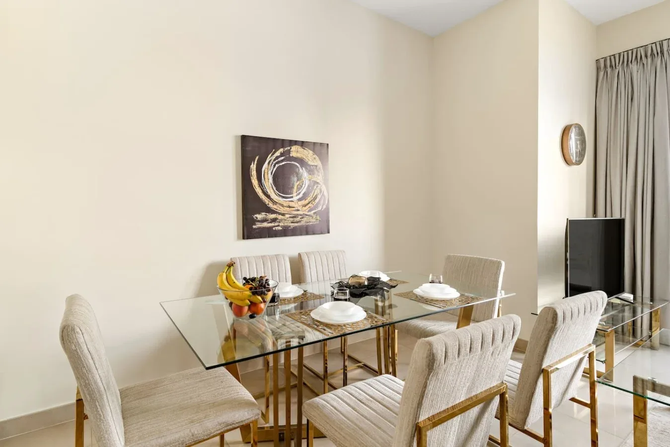 A dining area with a glass table and upholstered seating.
