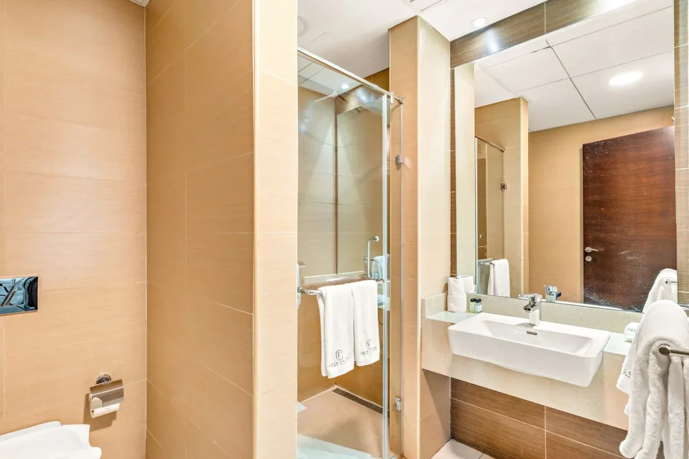 A bathroom with a glass shower and a sink beneath a large mirror.
