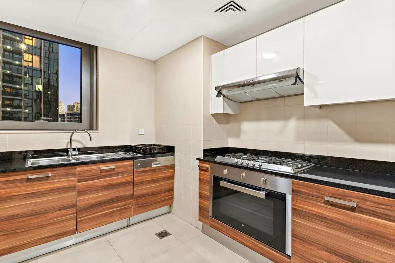A modern kitchen with wood-front cabinets and a large window.