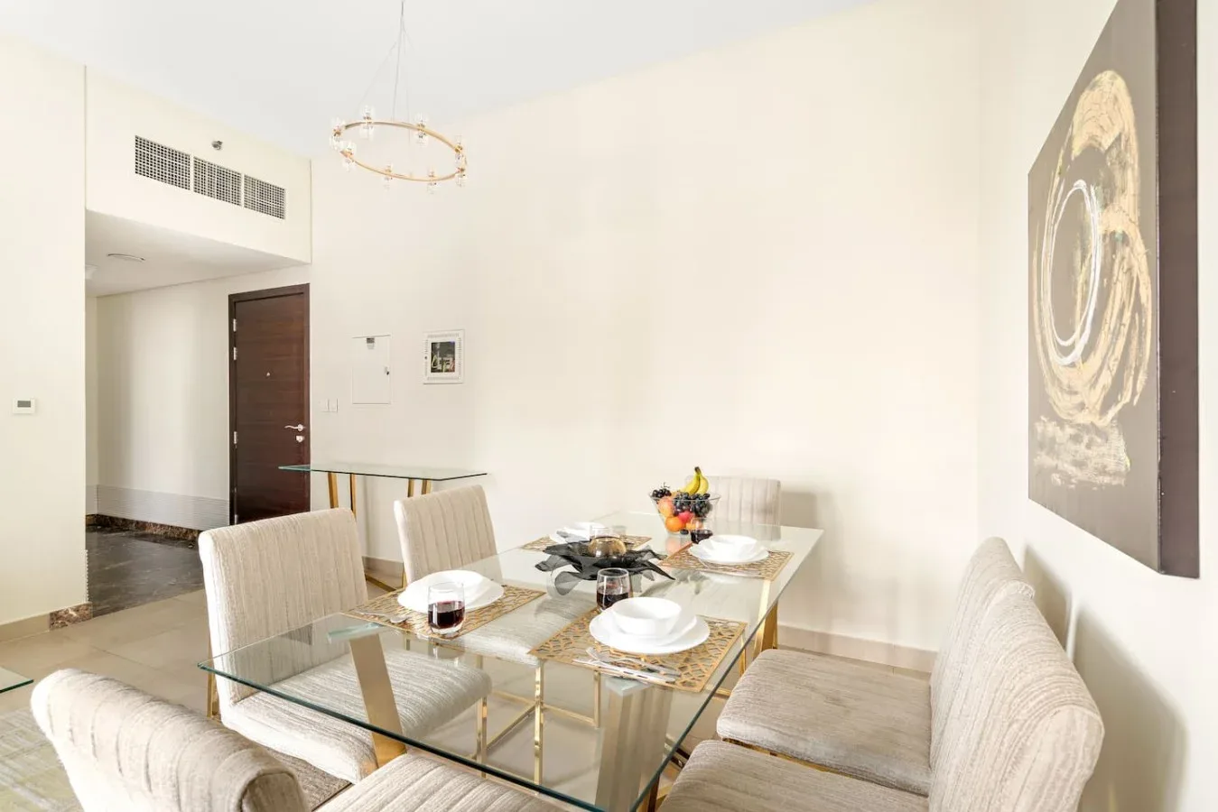 A dining area with a glass table set with dishes and upholstered seating.