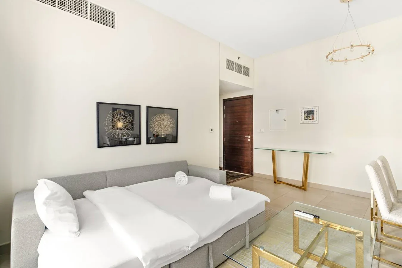 A bright bedroom with a large bed, framed artwork, and a small desk.