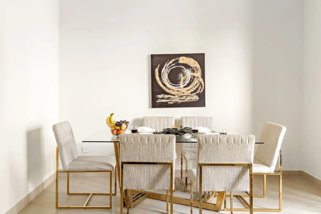 A dining area with a glass table and abstract artwork on the wall.