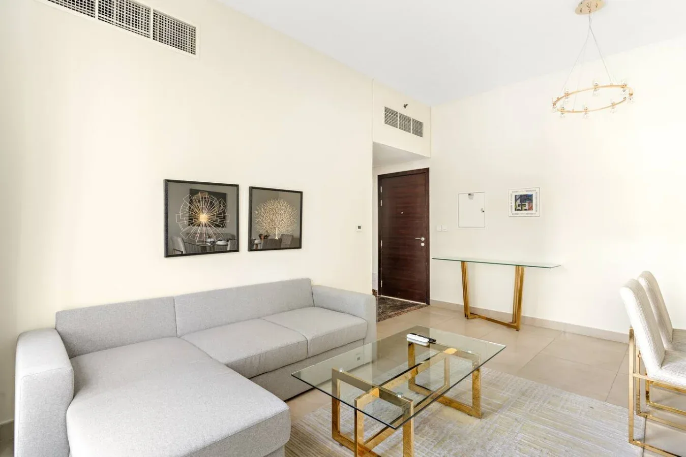 A bright living room with a sectional sofa and glass coffee table.