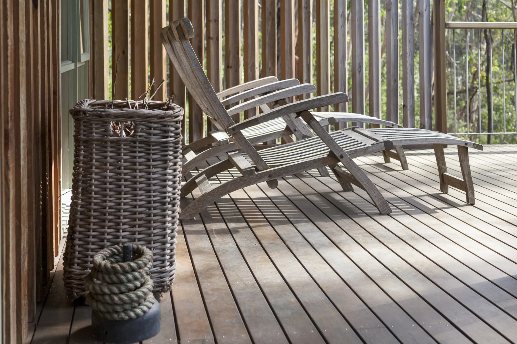 Una terraza de madera con asientos al aire libre junto a una barandilla de listones.