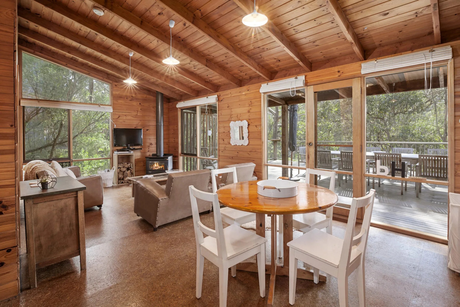 Una sala y comedor revestidos de madera se abren a una terraza mediante grandes ventanales.