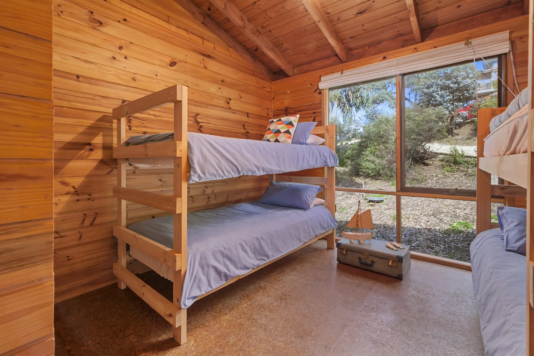 Un dormitorio revestido de madera con literas junto a una ventana grande.