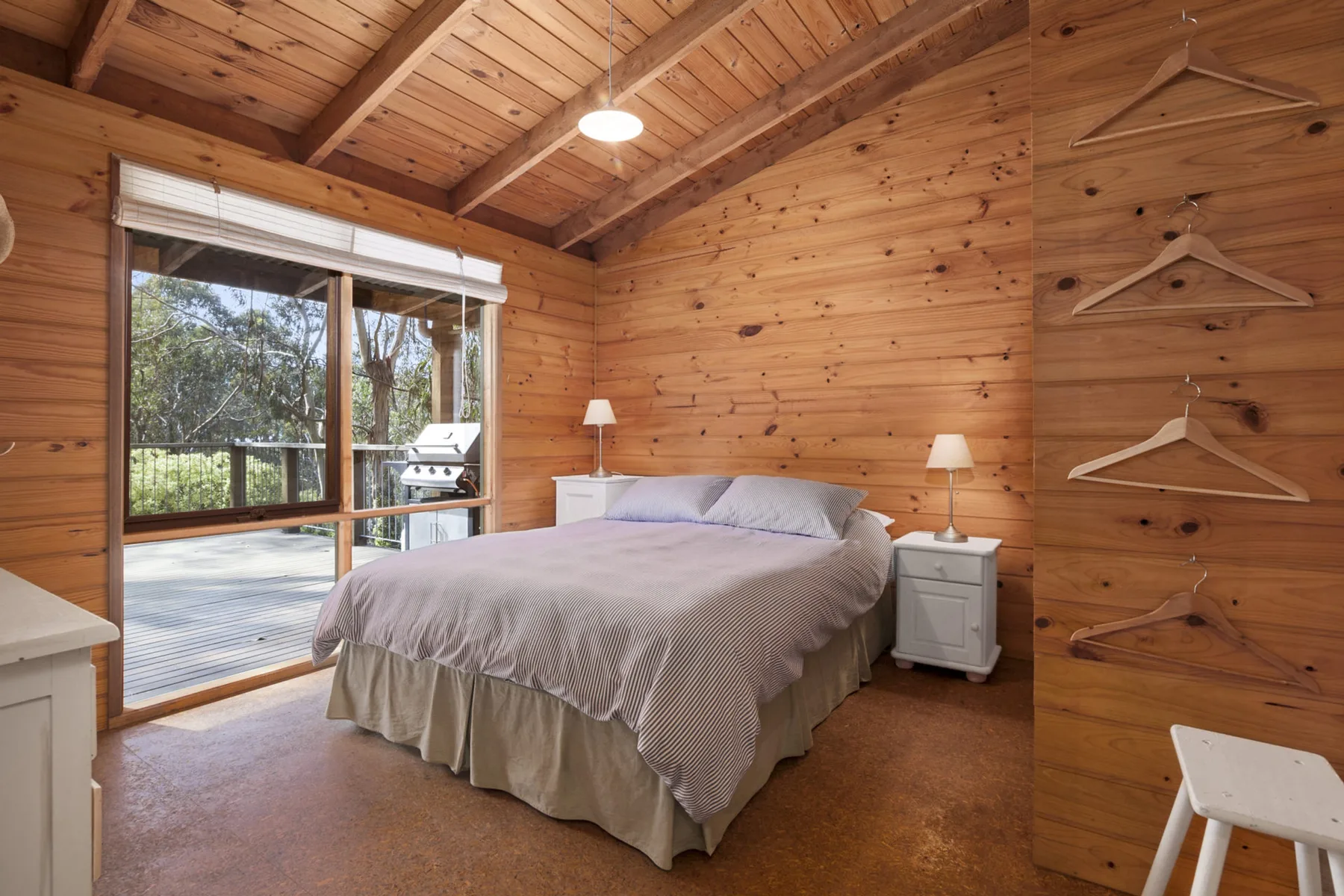 Un dormitorio revestido de madera con una cama junto a una puerta de vidrio amplia.