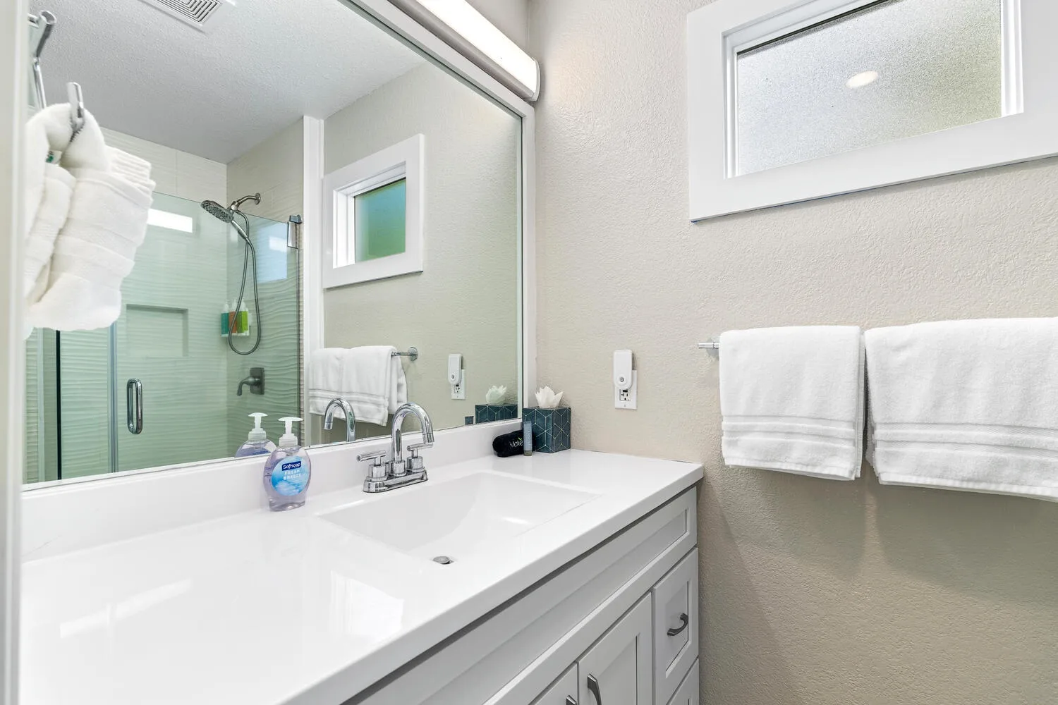Un baño luminoso con lavabo y ducha de vidrio.