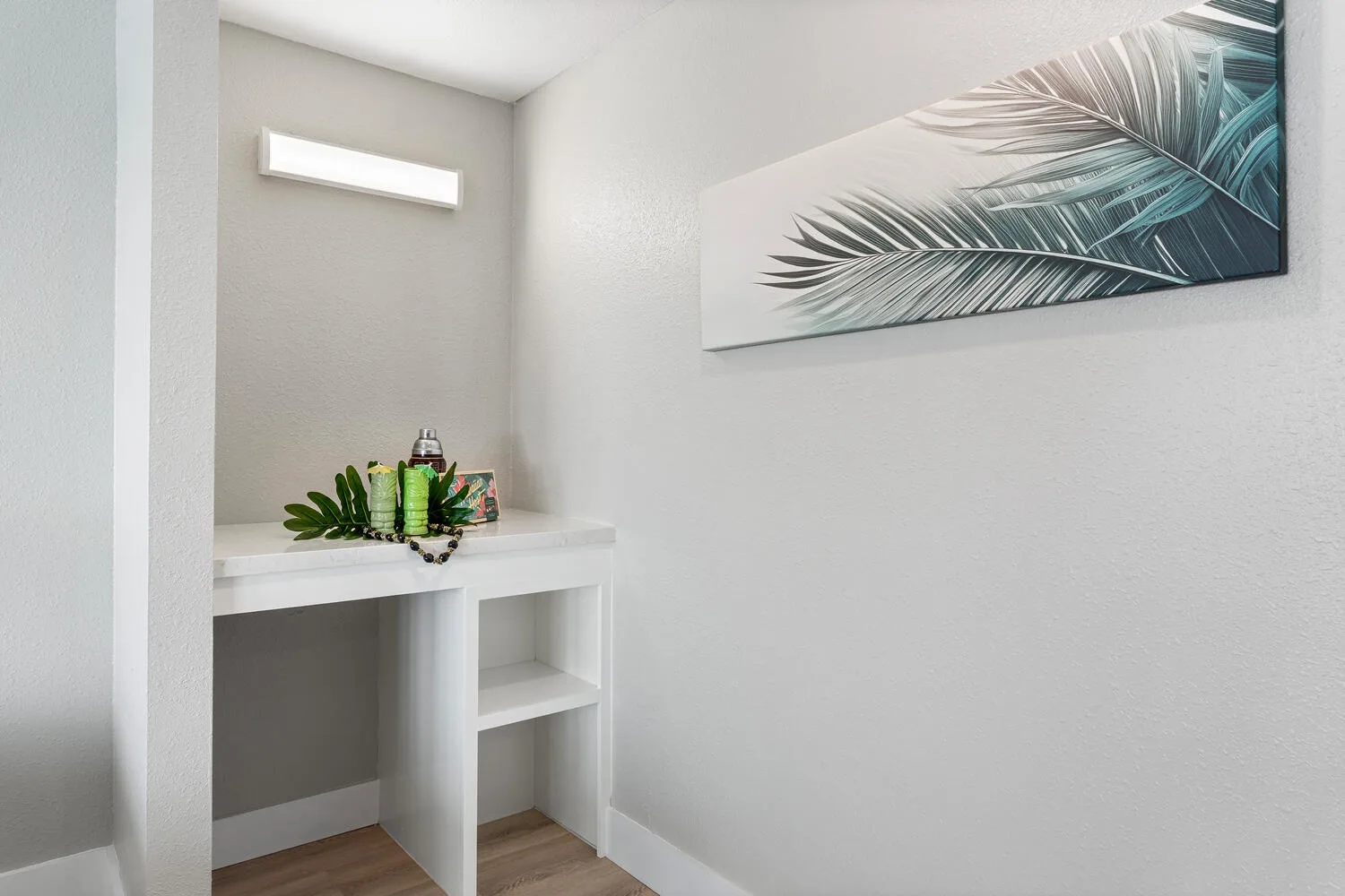 Un luminoso tocador con encimera, estantes abiertos y arte botánico en la pared.