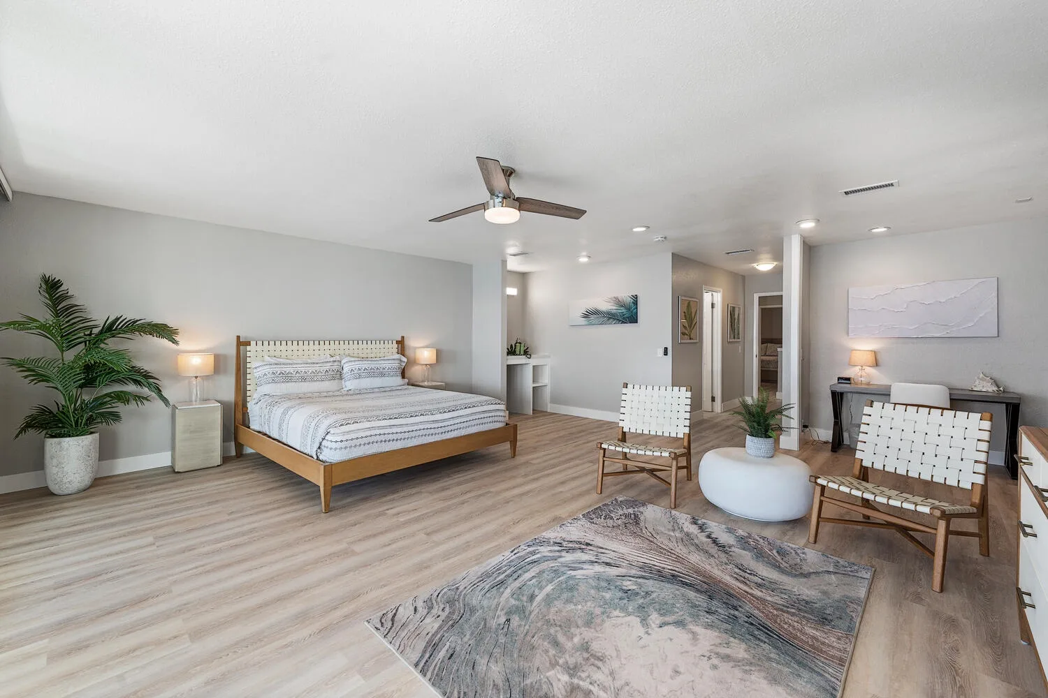 Un dormitorio luminoso con una cama de madera, asientos y un ventilador de techo.