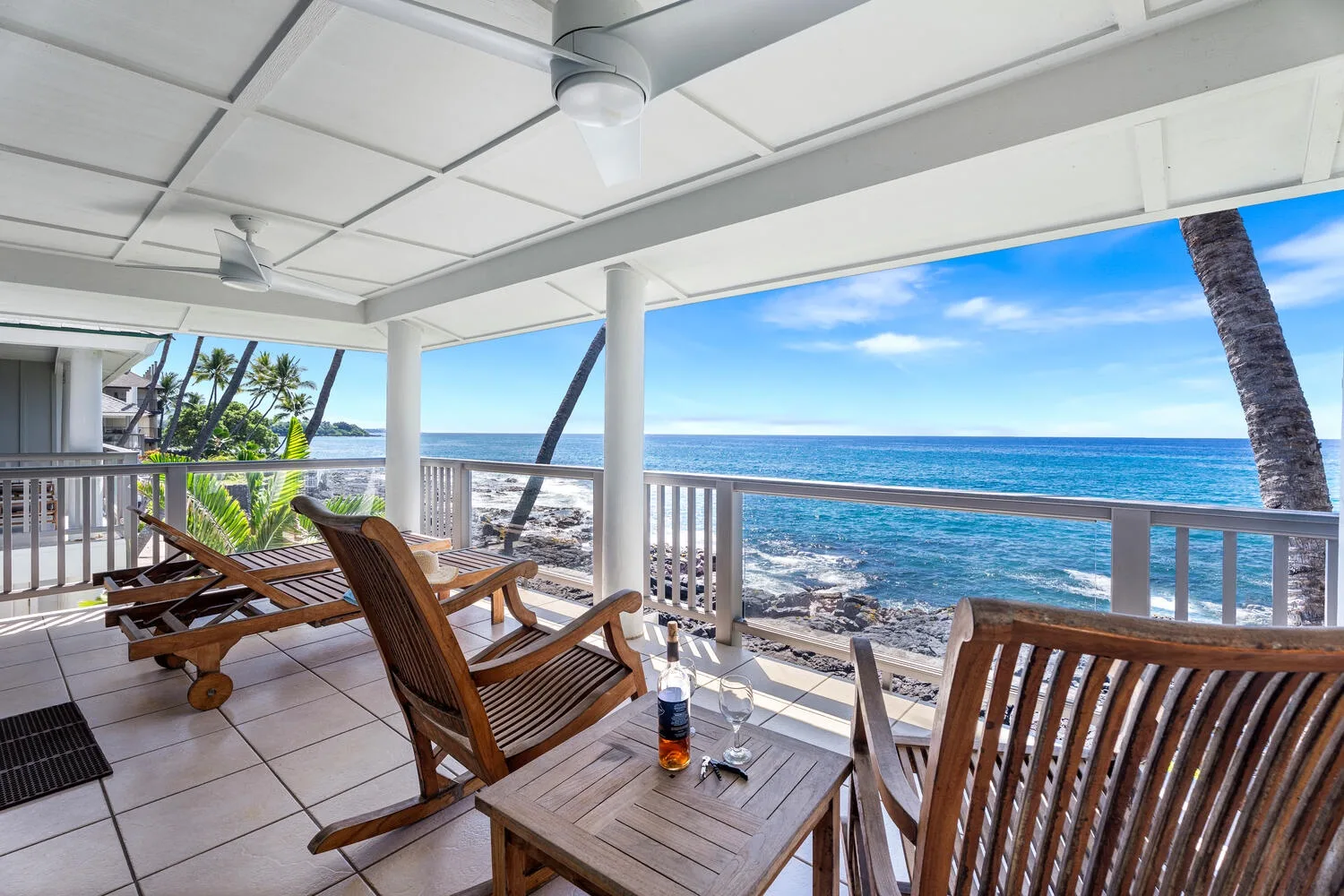 Un patio cubierto frente al mar tiene asientos de madera y vistas al océano.