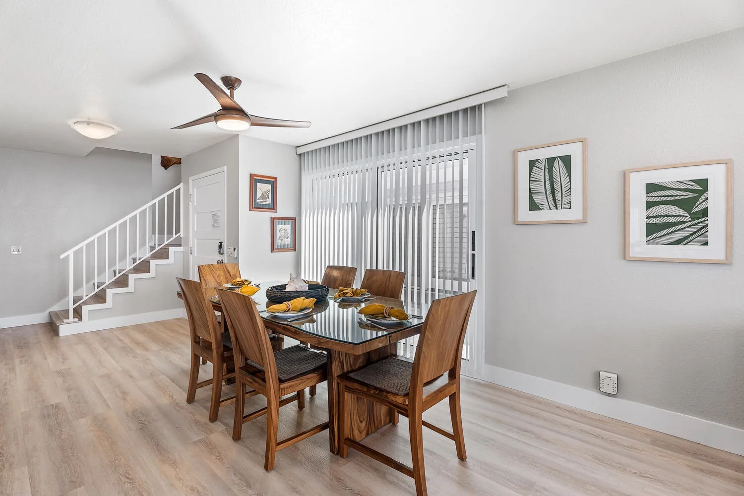Un comedor con una mesa de madera y sillas junto a grandes ventanas.