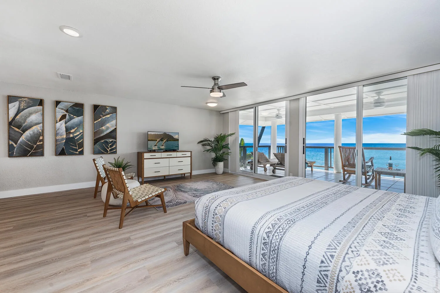 Dormitorio con cama, asientos y puertas corredizas de vidrio con vista al océano.