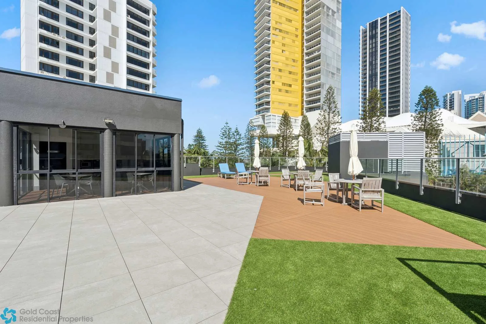 Una terraza al aire libre con asientos junto a un edificio moderno y un césped ajardinado.