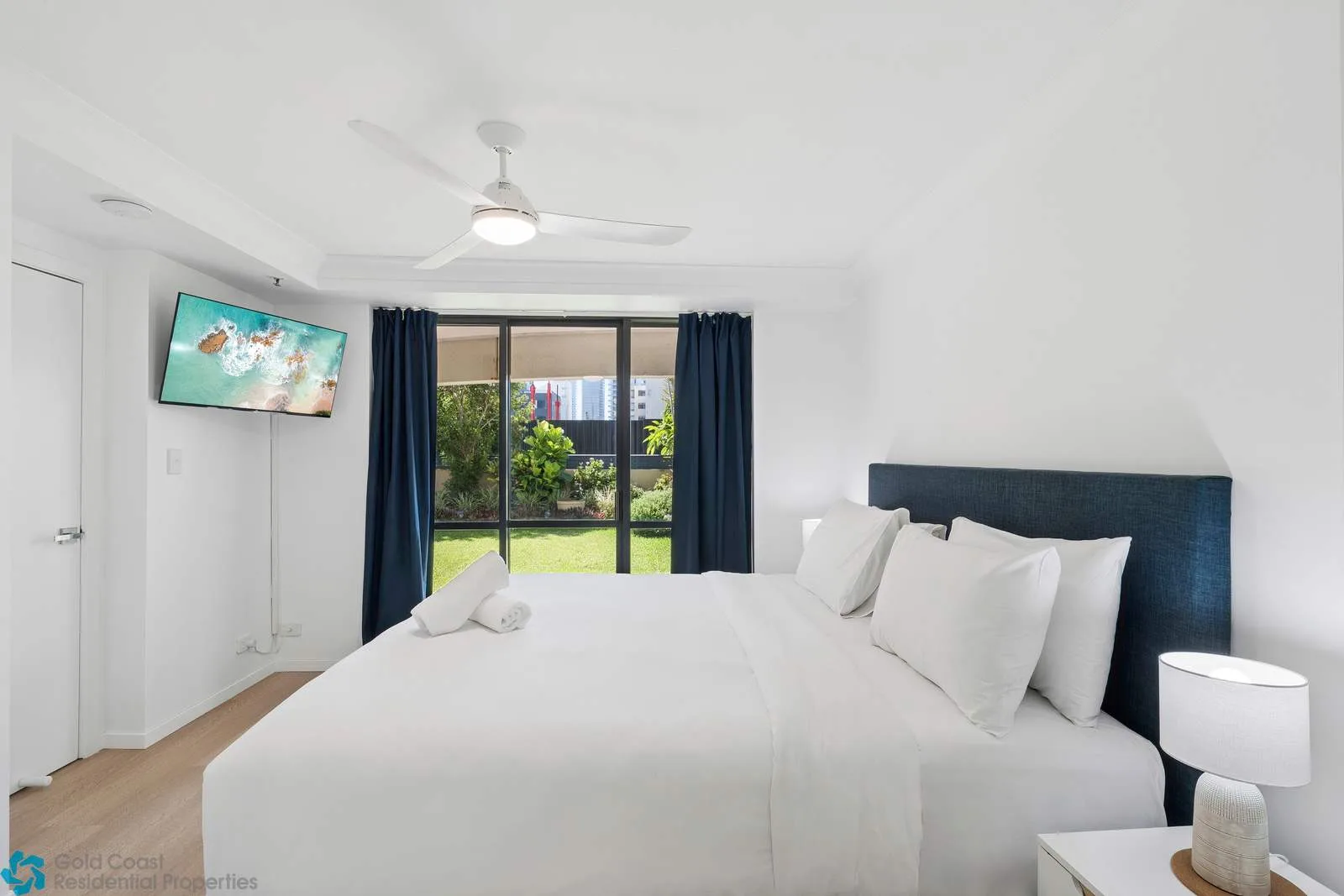 Un dormitorio luminoso con una cama grande y puertas corredizas de vidrio hacia una zona verde.