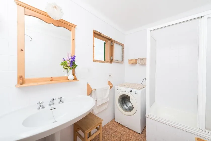 A bright bathroom with a sink, mirror, and washing machine.