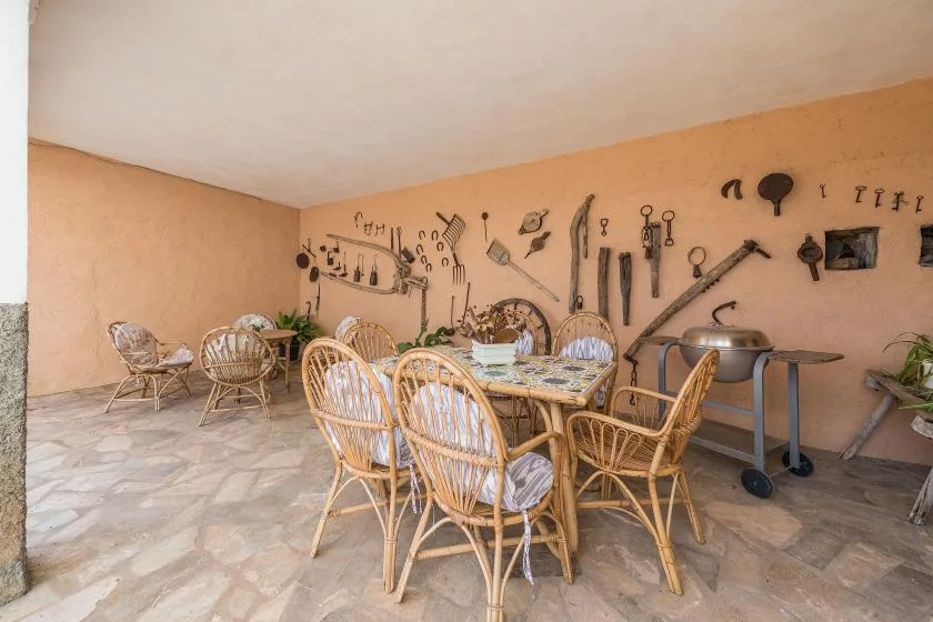 A dining area with wicker seating and decorative tools displayed on the wall.