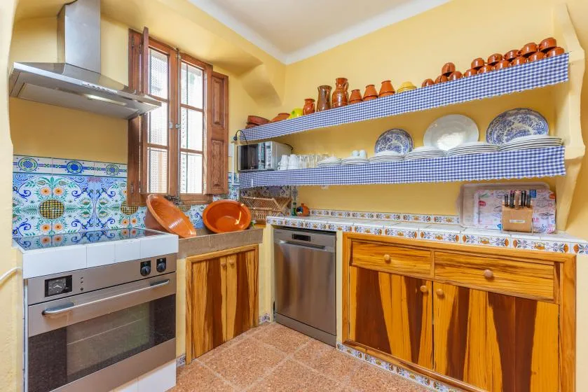A colorful kitchen with wooden cabinets, tiled walls, and open shelves.