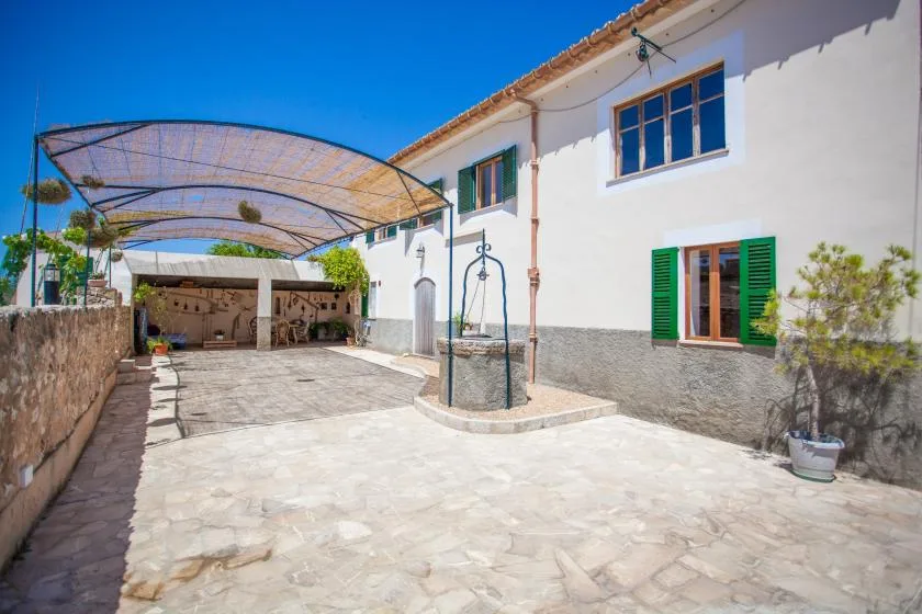 A paved courtyard with a covered seating area beside a white building.