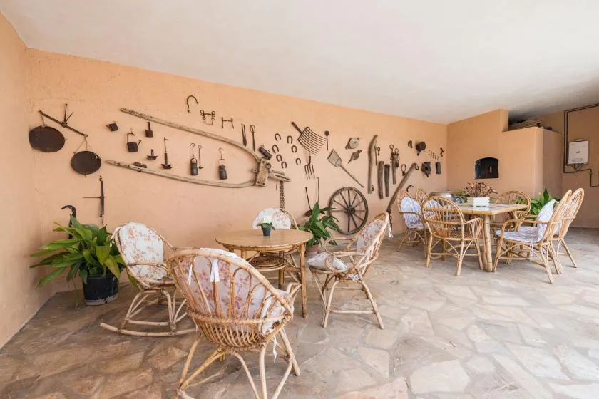 A rustic dining area with wicker seating and tools displayed along the wall.