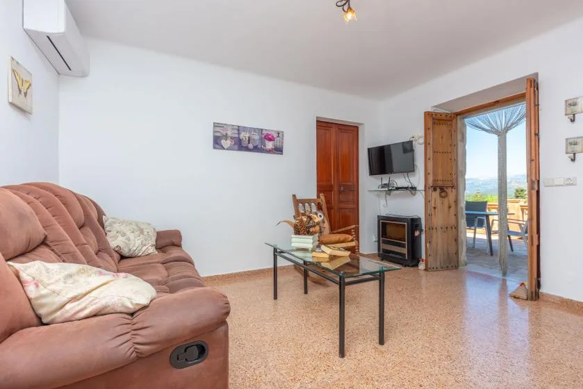 A living room with seating, a glass coffee table, and an open door to a balcony.