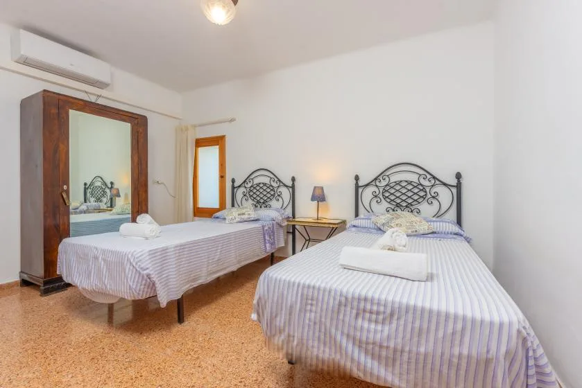 A bedroom with two beds and a bedside table.