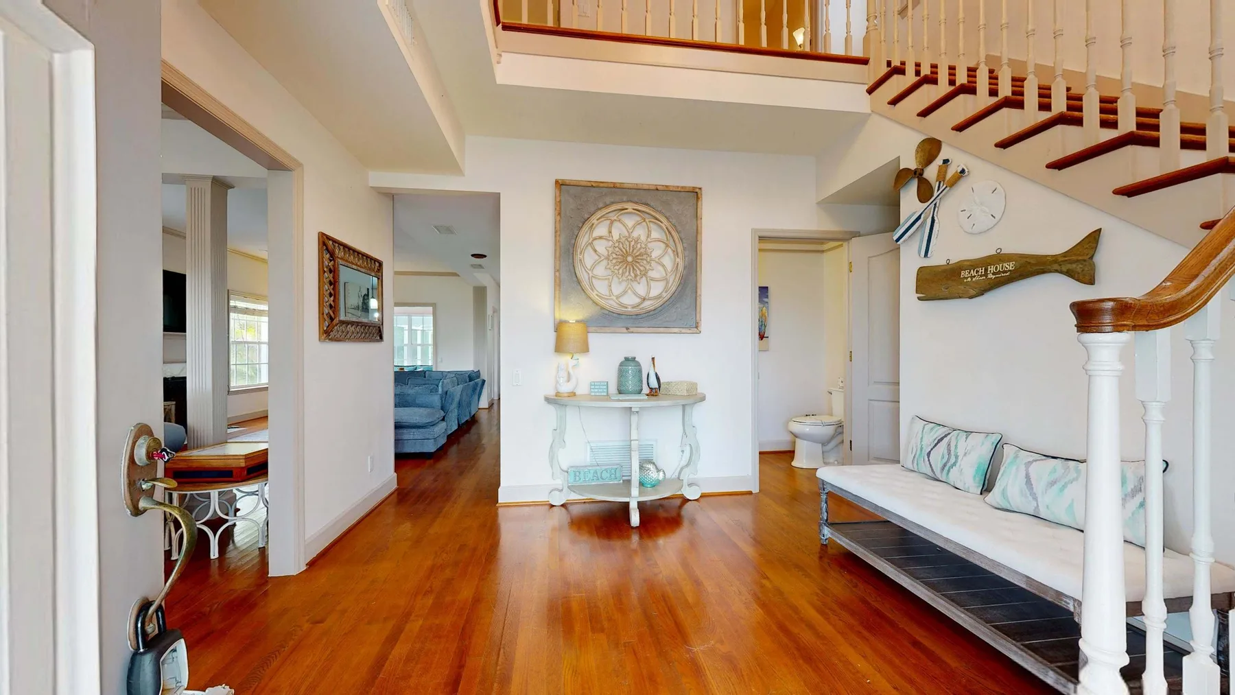 A bright interior hallway with polished wood flooring and a staircase.