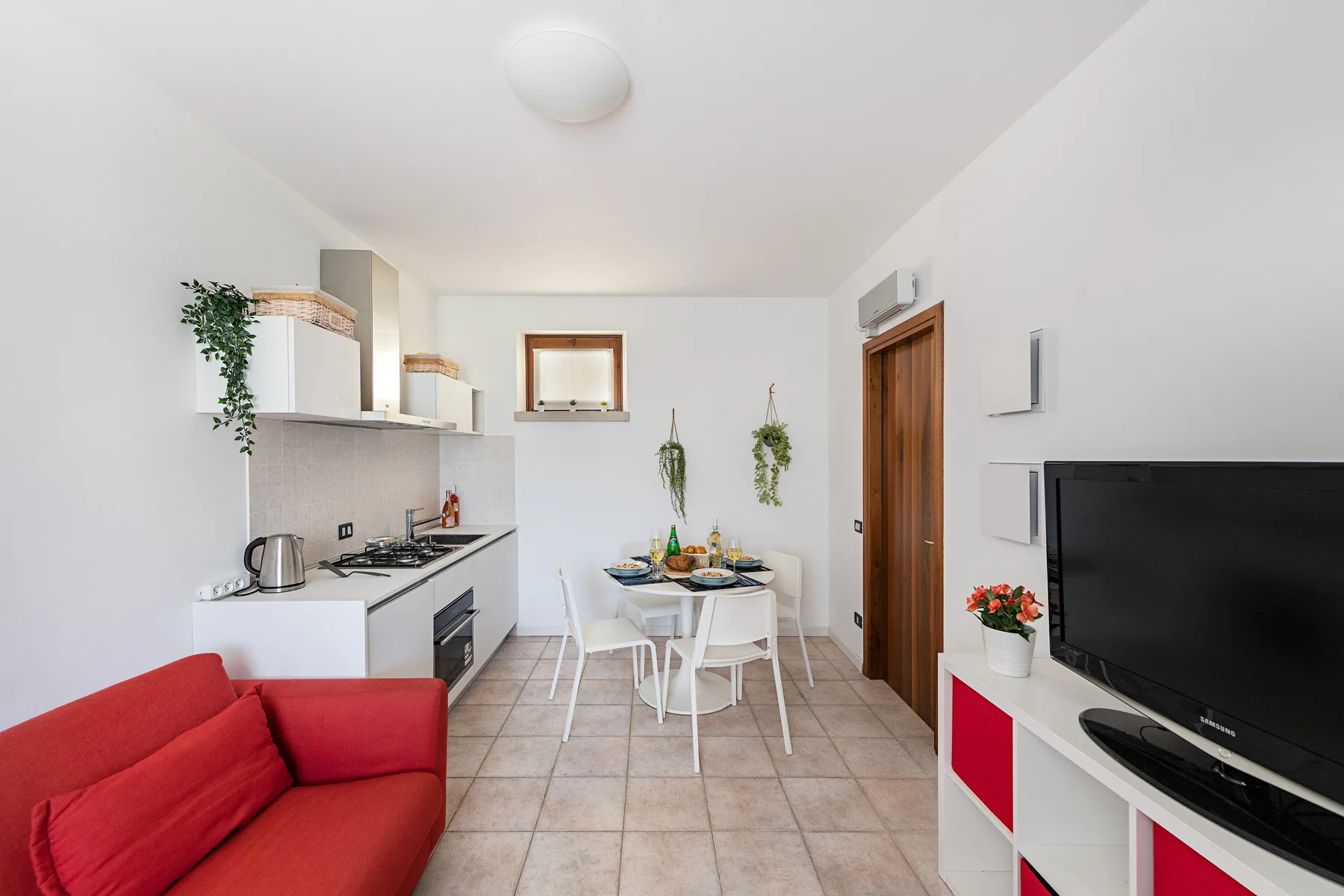A bright kitchen and dining area with a red sofa and a small table.