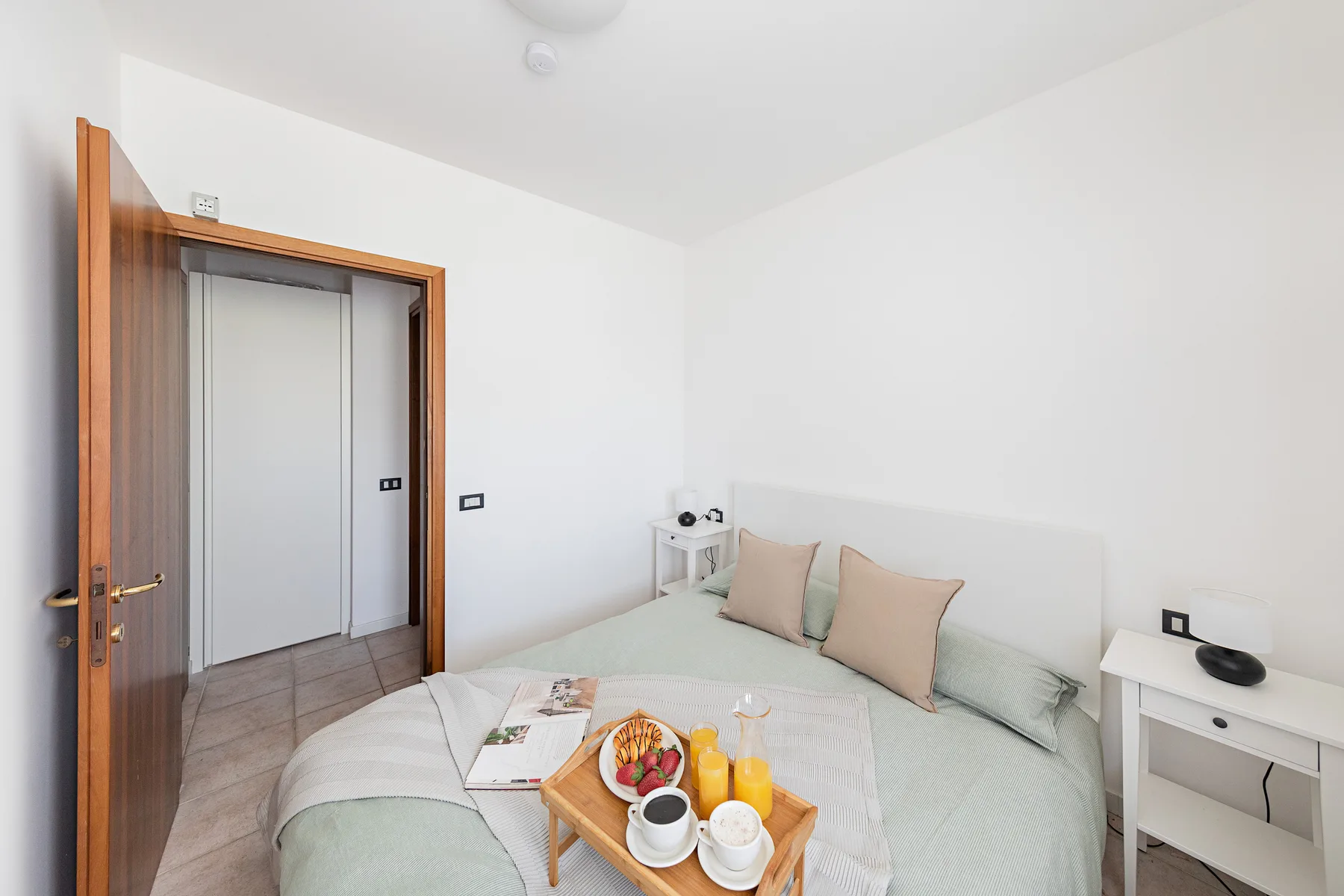 A bright bedroom with a bed and small bedside tables.