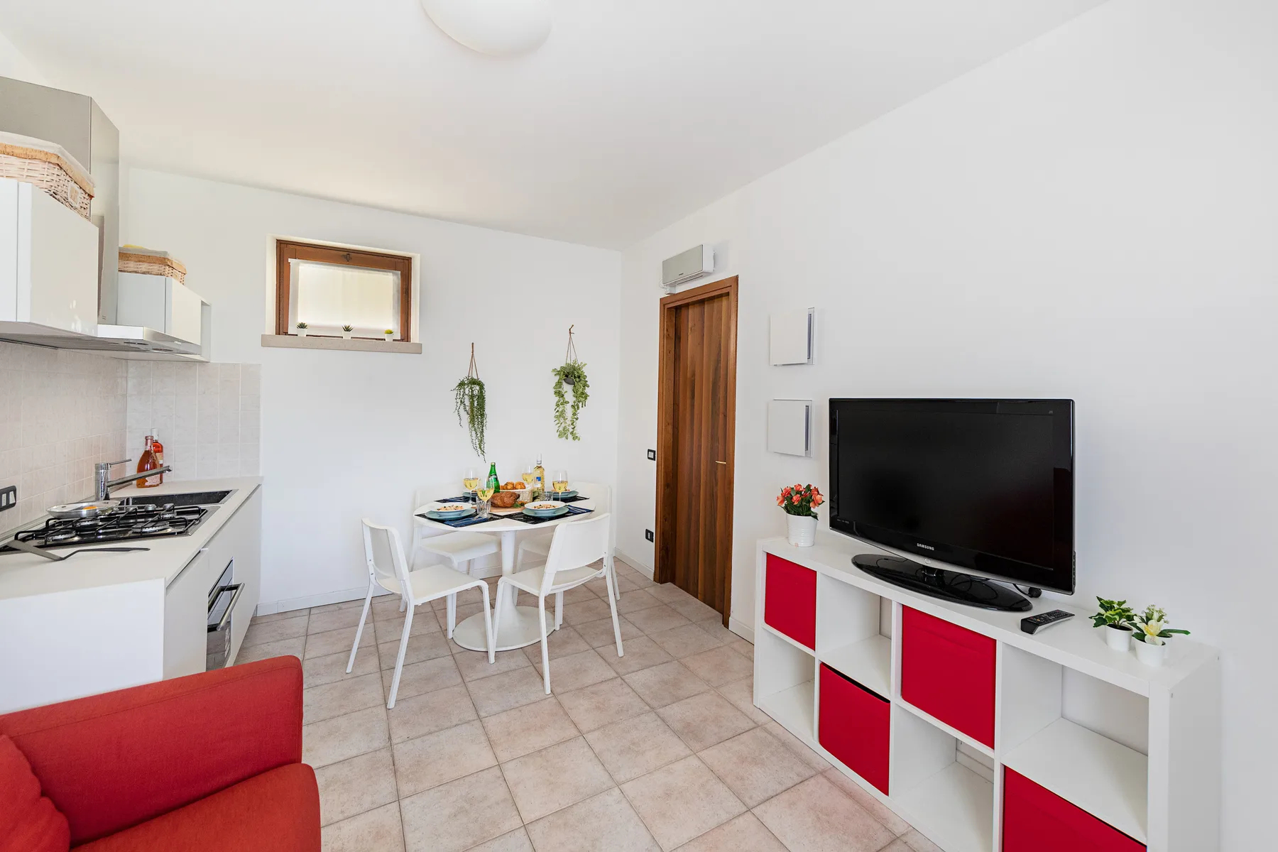 A bright living and dining area with a kitchen counter and television.
