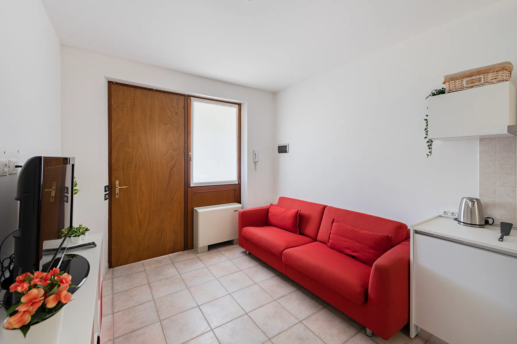 Una pequeña sala de estar con un sofá rojo junto a la entrada.