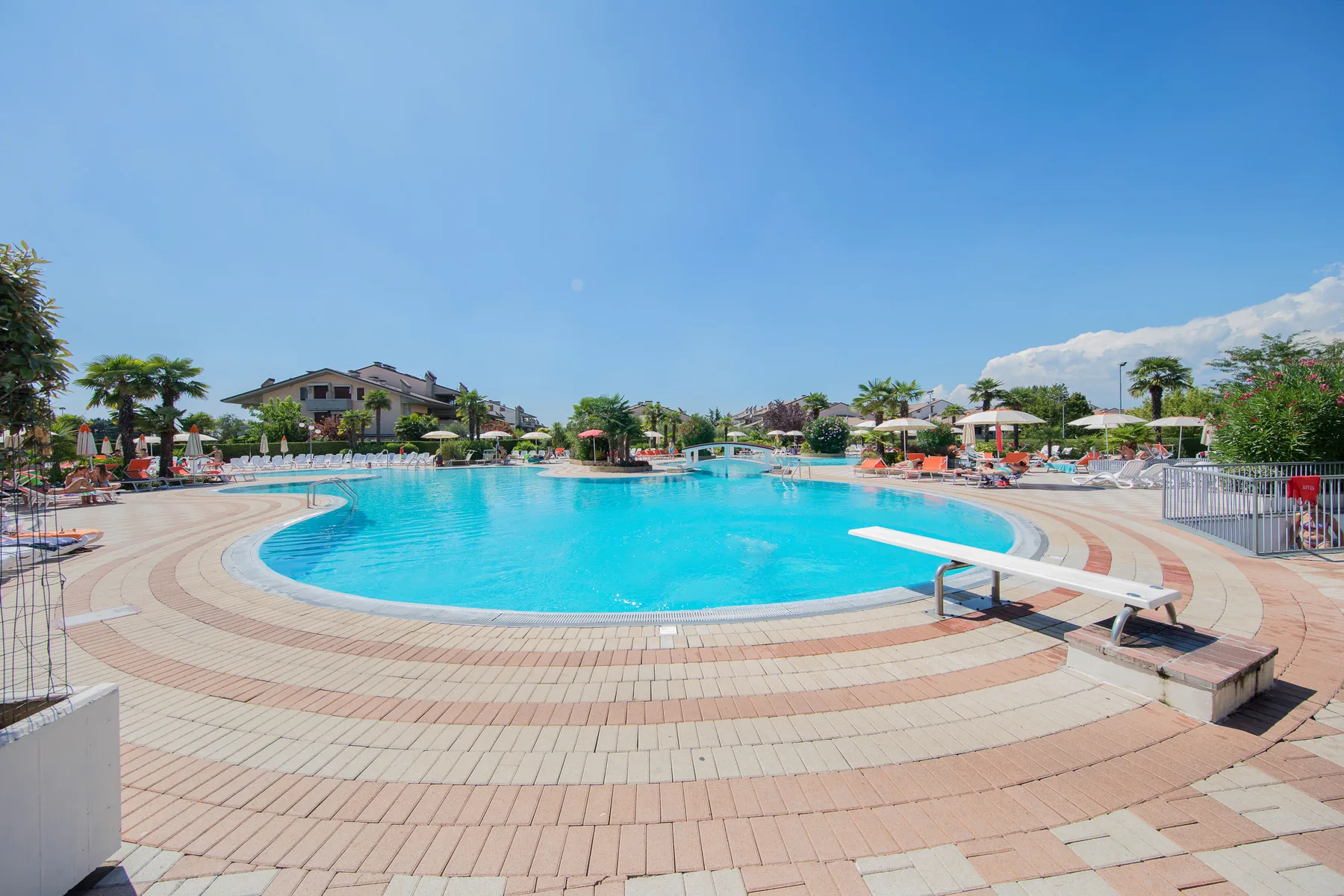 A large outdoor swimming pool is surrounded by a paved deck and lounge seating.