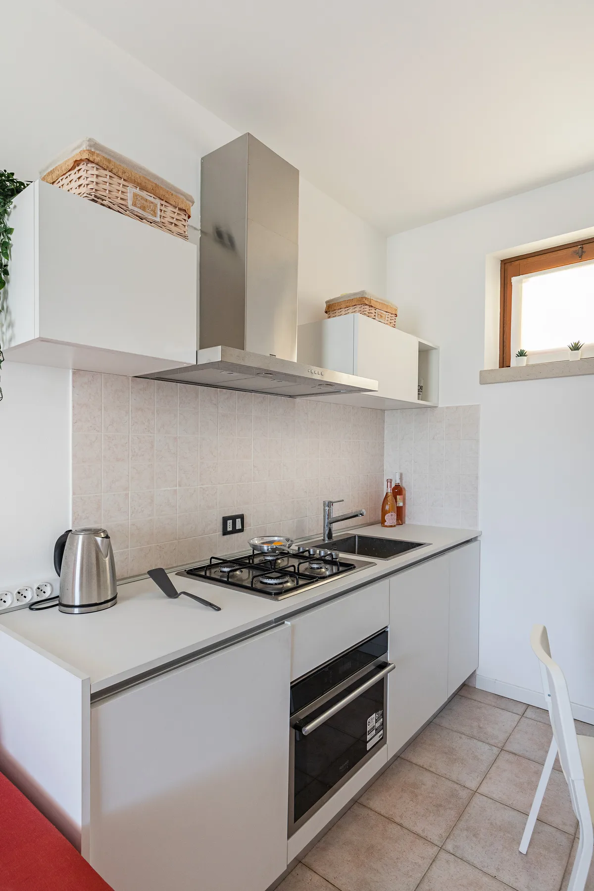 A compact kitchen with white cabinets, a gas cooktop, and a built-in oven.