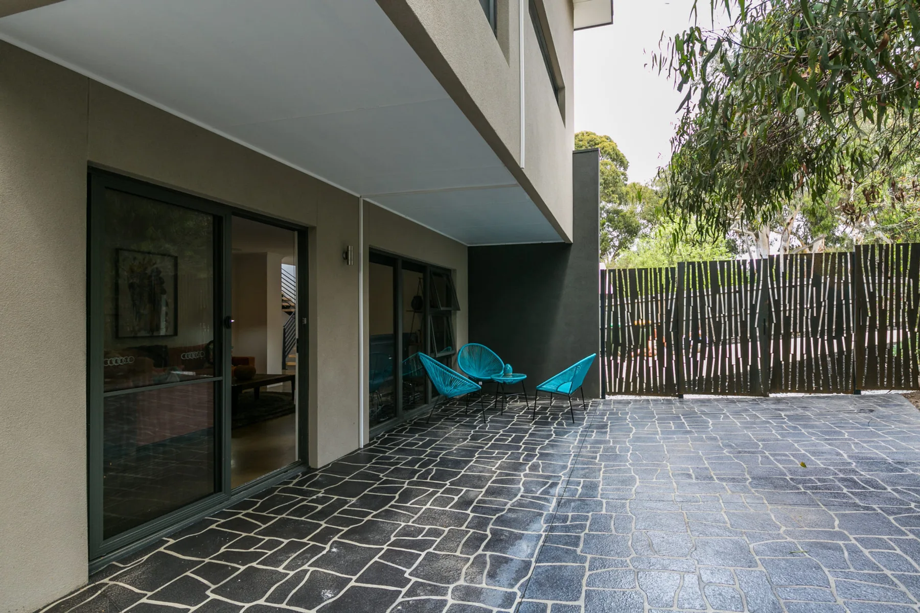 Un patio exterior pavimentado con asientos azules junto a un edificio moderno.