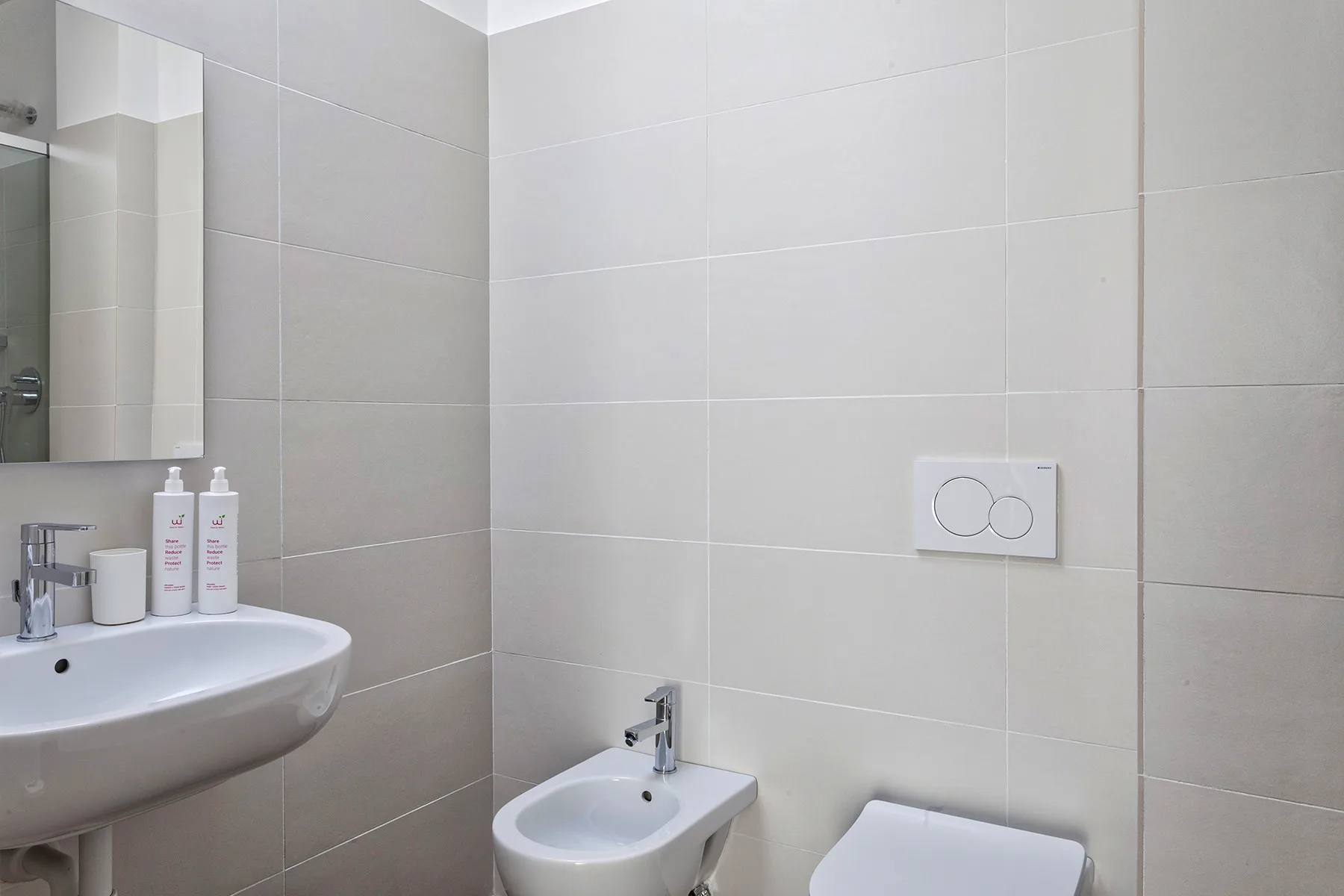 Un baño con paredes alicatadas, lavabo, bidé e inodoro.
