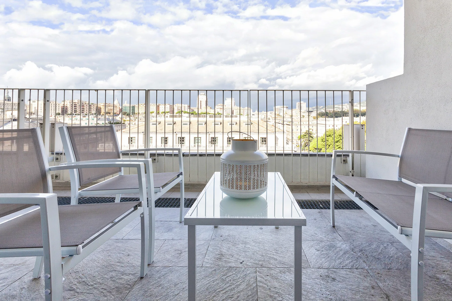Una zona de estar en un balcón con una mesa de vidrio y vistas a la ciudad.