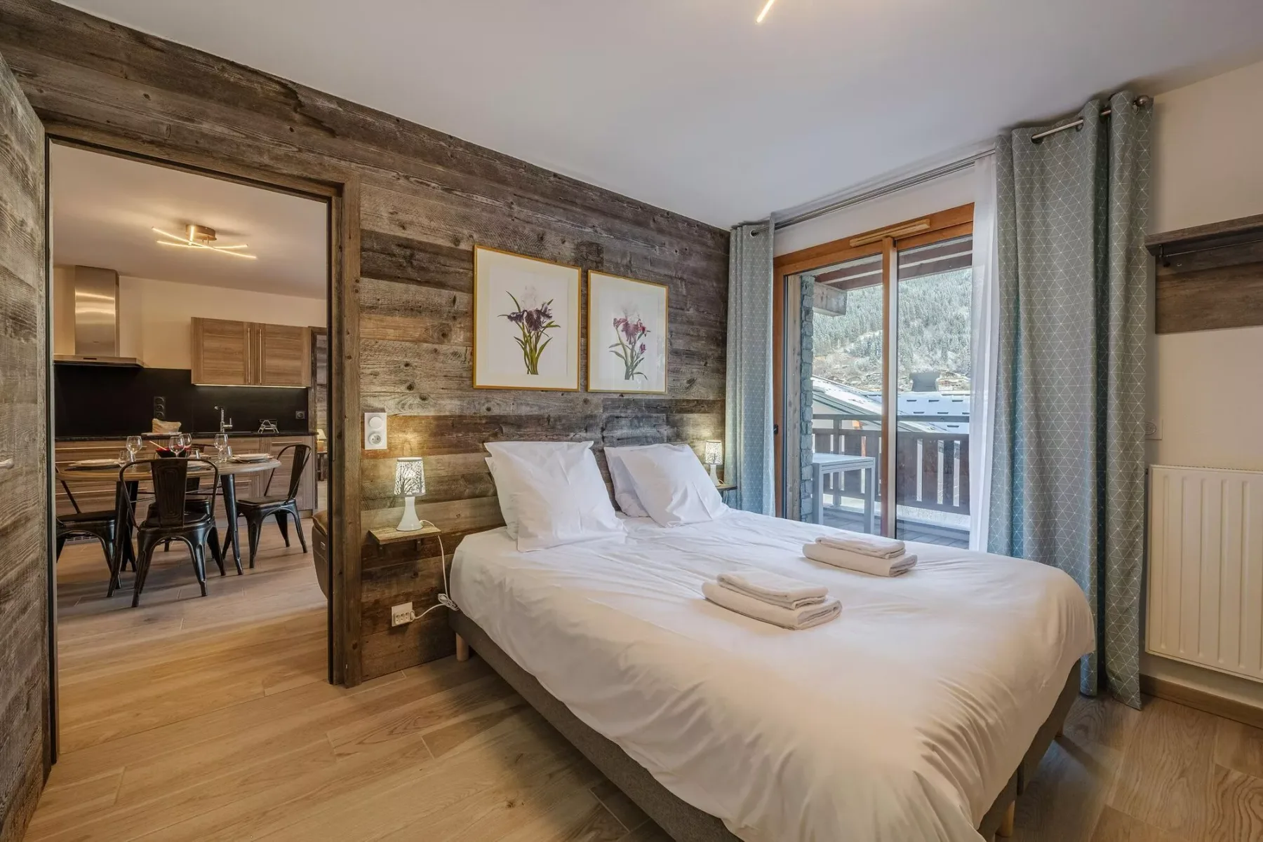 A bedroom with a double bed beside a window and balcony doors.