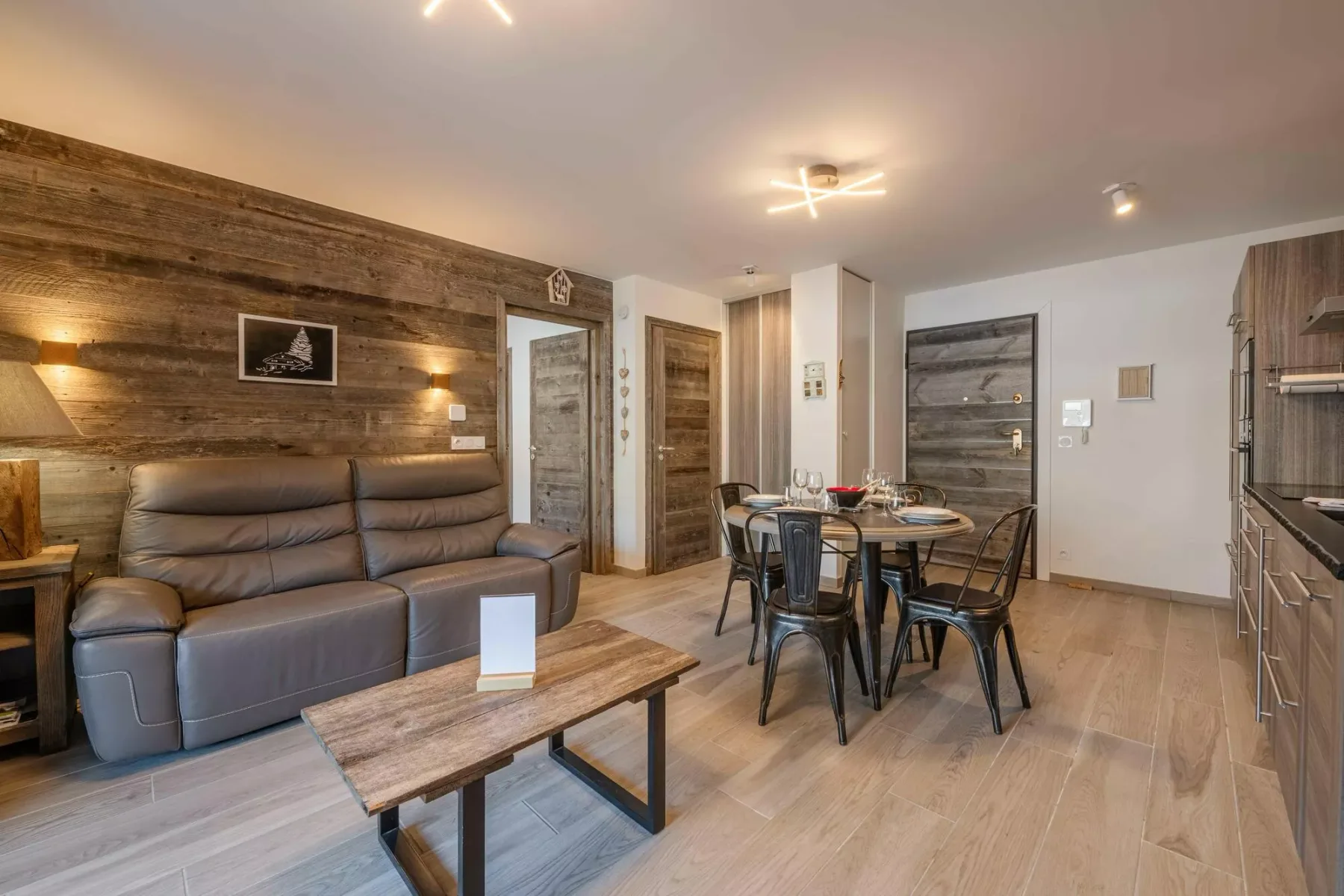 A living and dining area with seating, a dining table, and wood-paneled walls.
