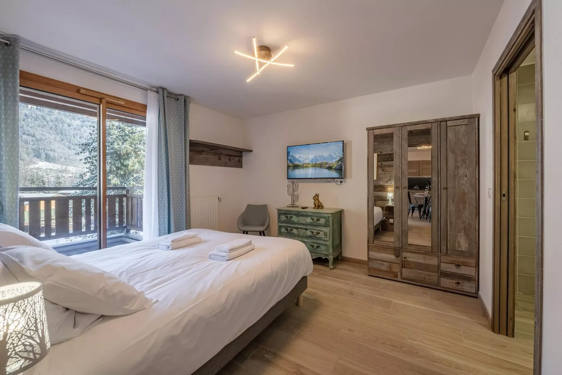 A bedroom with a neatly made bed beside a large window.