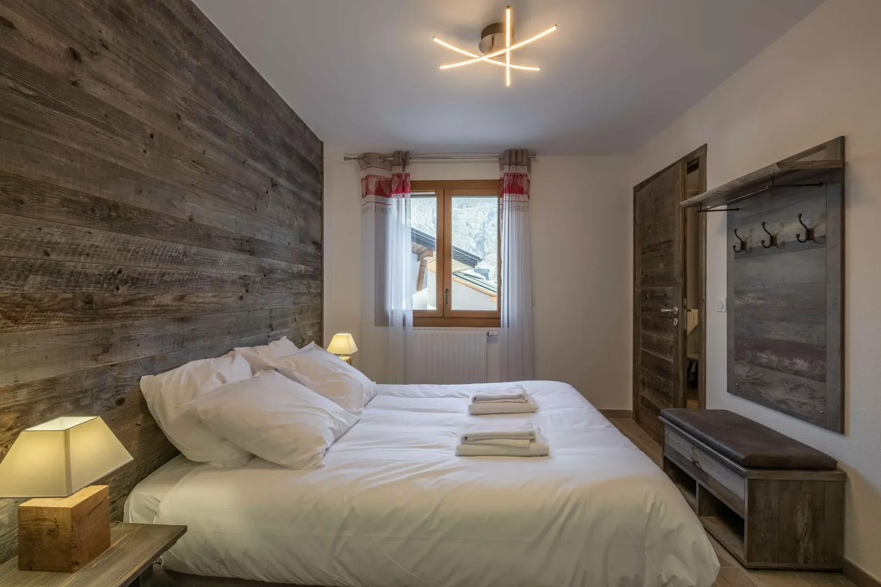 A bedroom with a large bed and a window with curtains.