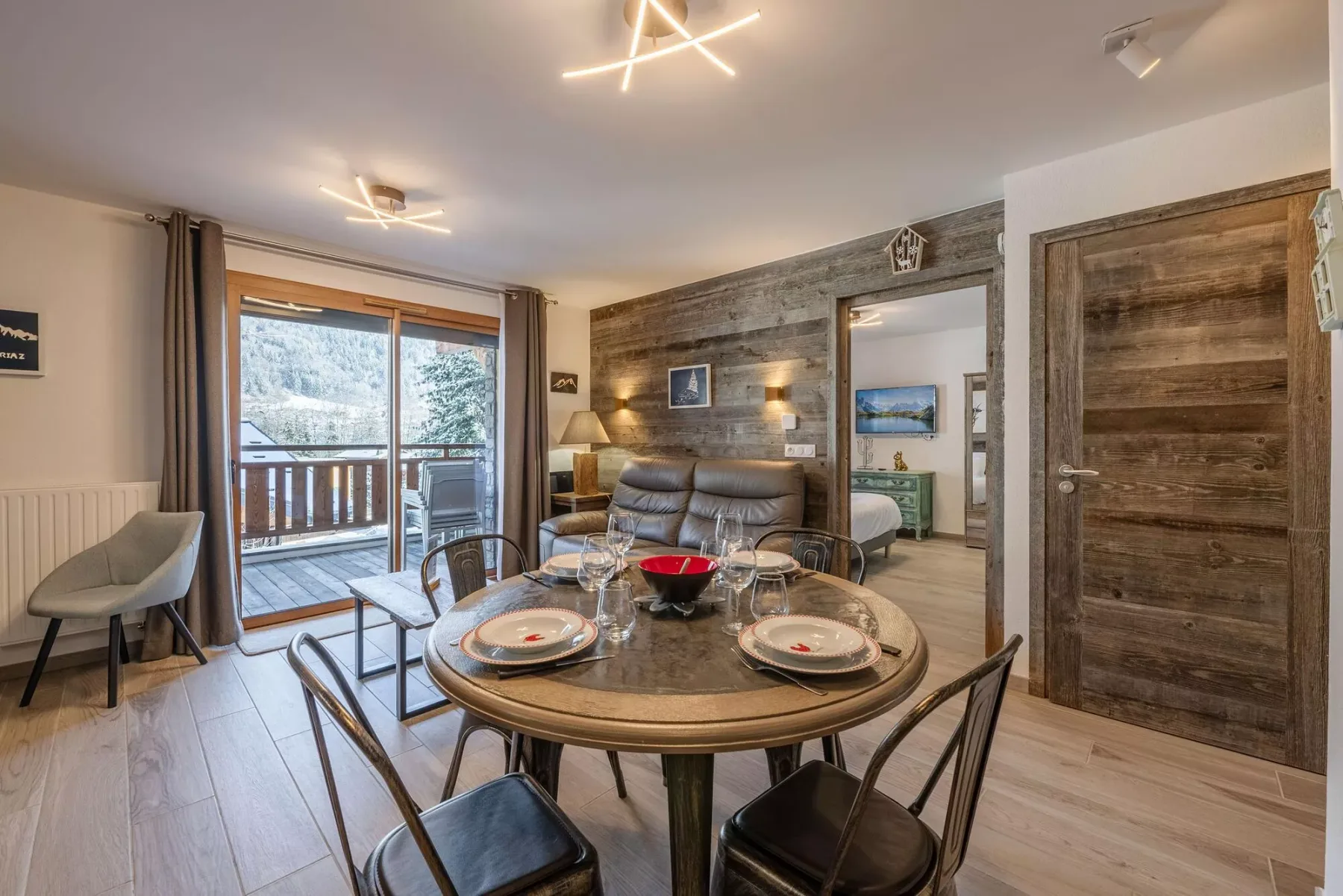 A living and dining area with a round table and seating beside a balcony.