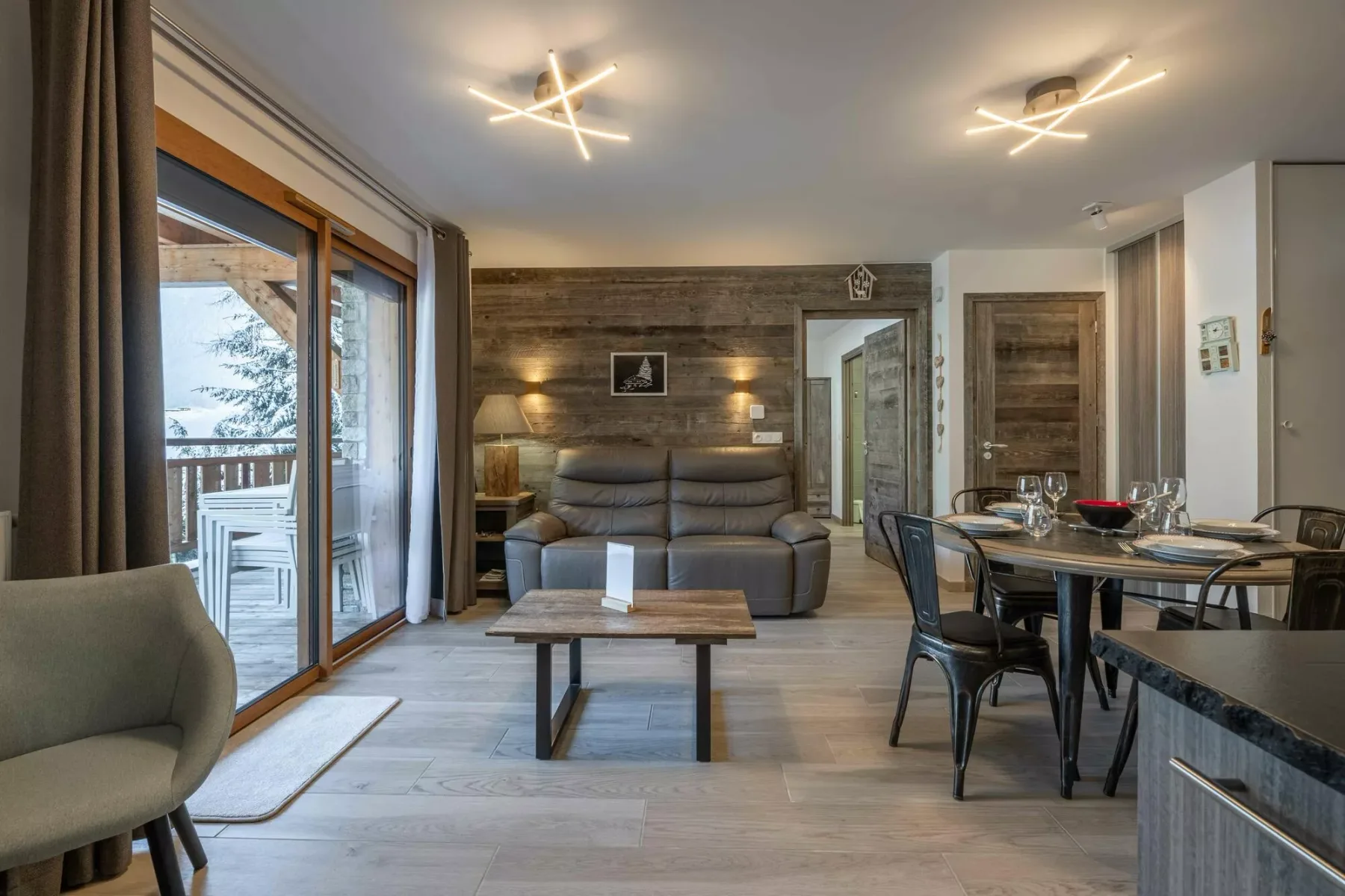 A living and dining area with seating, a coffee table, and a large window.