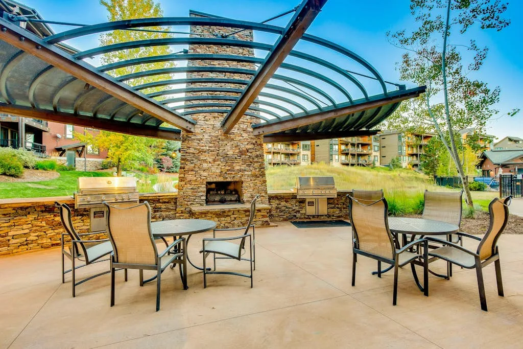 Un patio al aire libre con asientos bajo una cubierta curva y una chimenea de piedra.