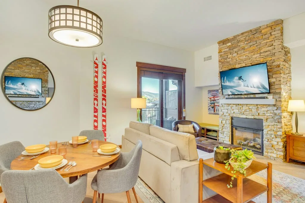 Una sala de estar con mesa de comedor, asientos y una chimenea de piedra.
