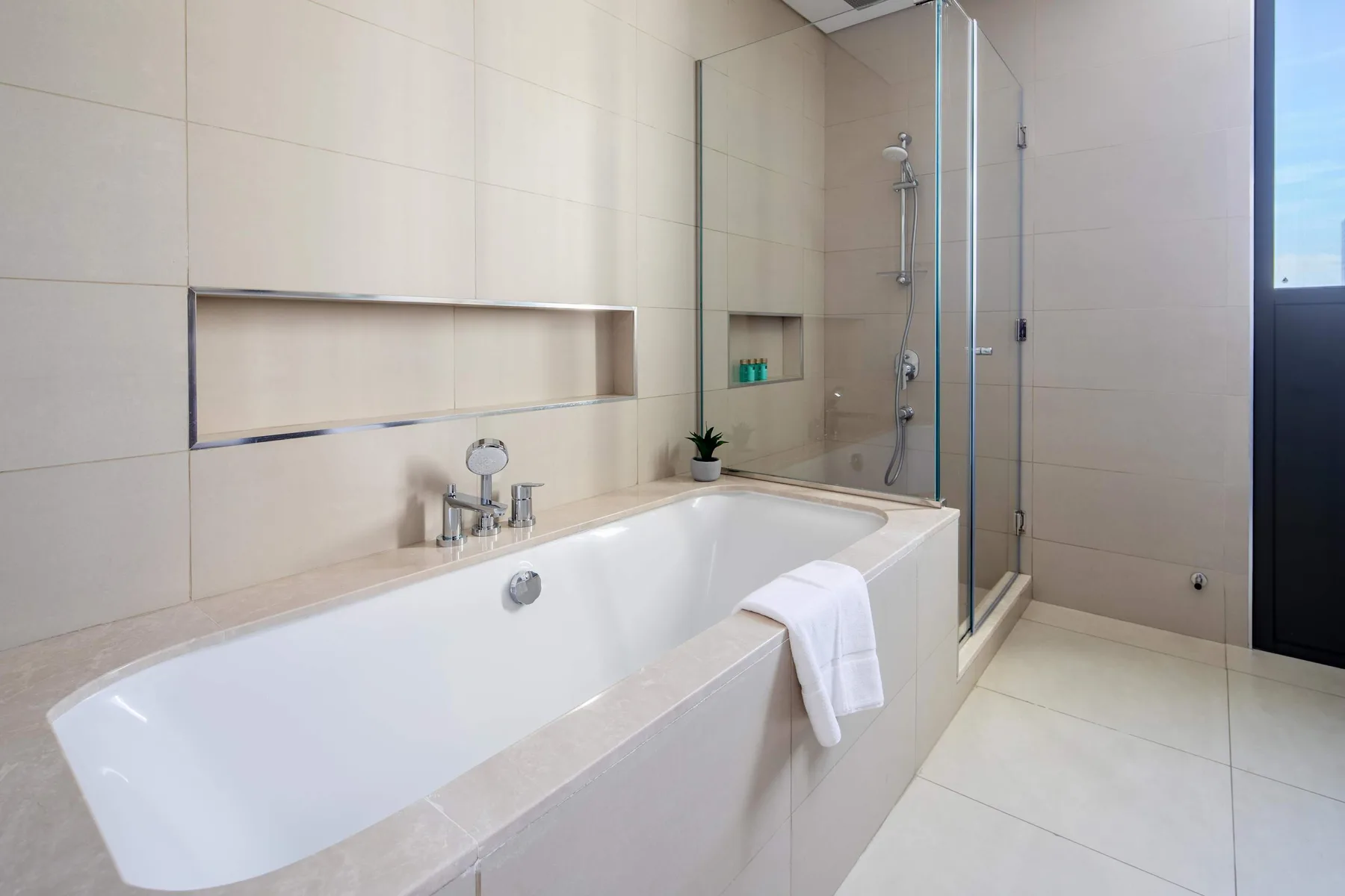 A tiled bathroom with a bathtub and glass shower.
