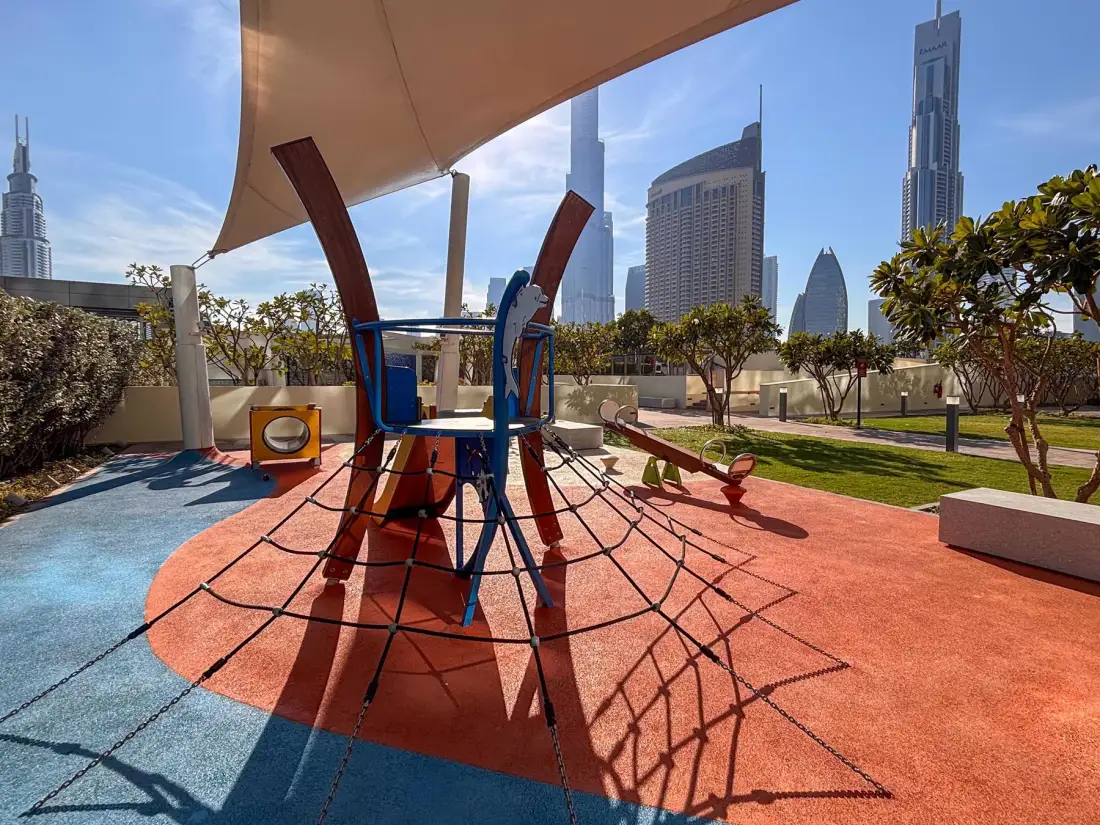 A rooftop playground with colorful climbing equipment and city towers in the background.