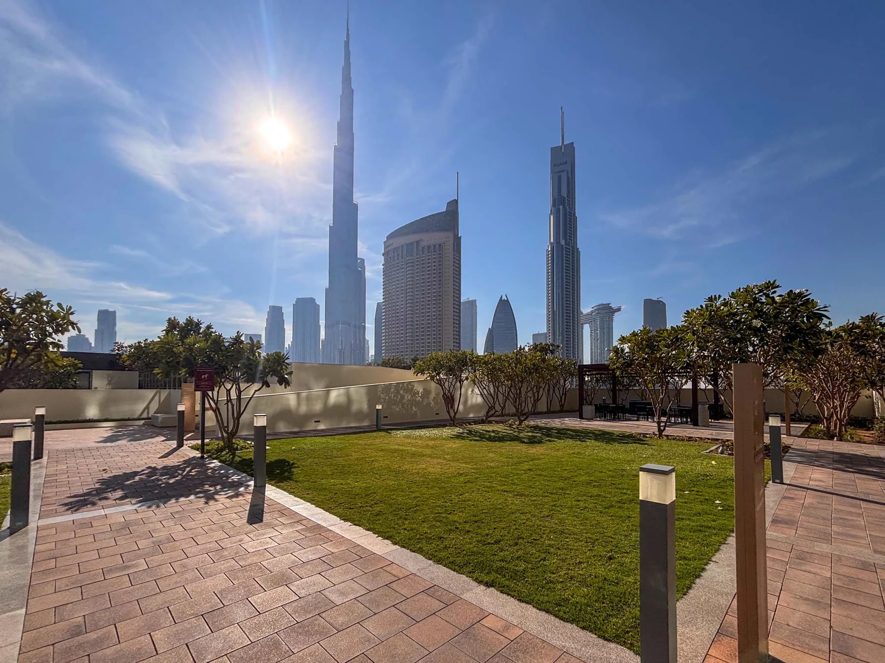 A landscaped rooftop terrace with paved walkways and a city skyline in the background.