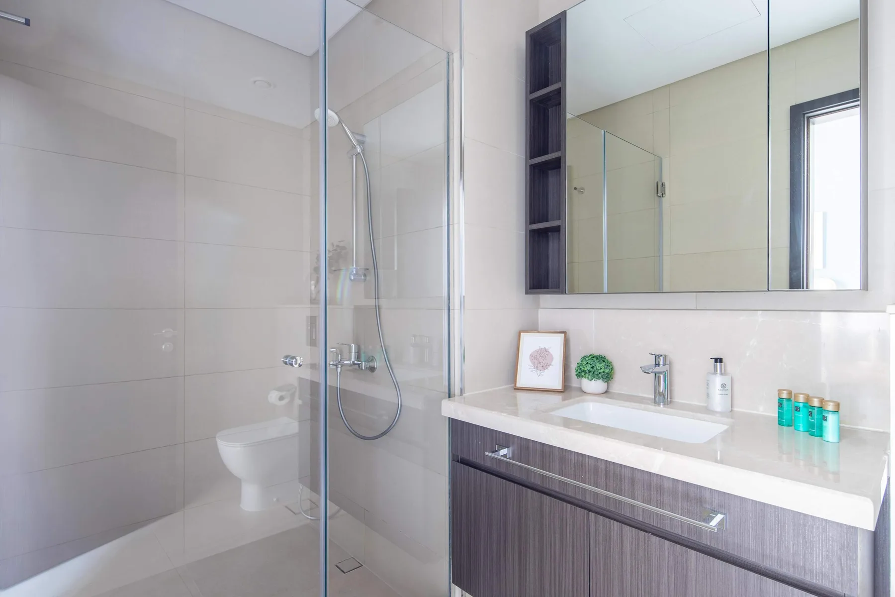 A modern bathroom with a glass shower and a wide vanity beneath a mirror.